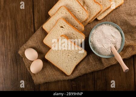 Fette di pane con ciotola di farina e uova Foto Stock