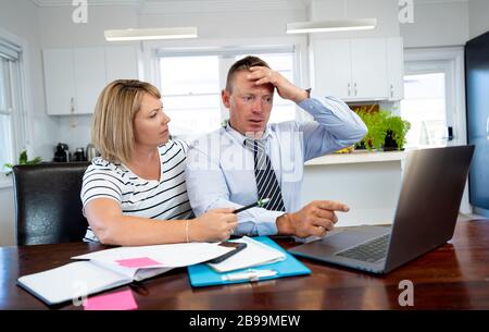 Recessione economica del coronavirus. Coppia di famiglia con maschere in difficoltà sopra le finanze domestiche e i debiti di piccola impresa durante la quarantena e la chiusura. impac Foto Stock