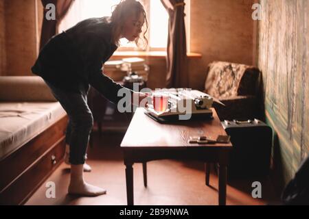 Giovane donna che tiene una tazza di tè in piedi nel soggiorno a casa Foto Stock
