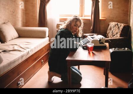 Giovane scrittore femminile seduto da macchina da scrivere a casa Foto Stock