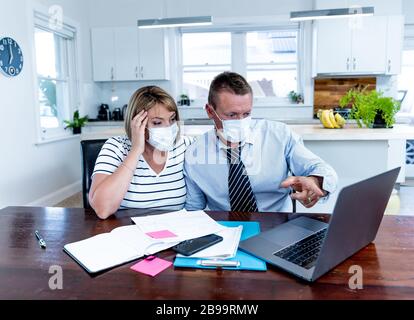 Recessione economica del coronavirus. Coppia stressata con maschere in auto-isolamento sopra le finanze domestiche e i debiti di piccola impresa durante la chiusura di quarantena. i Foto Stock