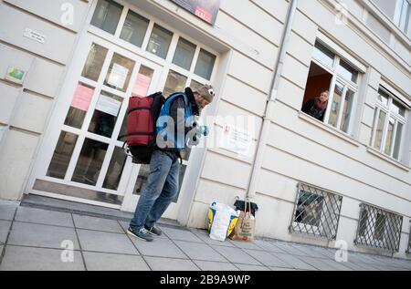 Stoccarda, Germania. 23 marzo 2020. Michael Müller (l), visitatore del centro di assistenza ai senzatetto Olga 46, si erge di fronte all'ingresso del centro di assistenza, Gabriele Großhans, operatore sociale, si affaccia dalla finestra. Anche i senzatetto del Baden-Württemberg sono colpiti dalla crisi di Corona. Credit: Marijan Murat/dpa/Alamy Live News Foto Stock