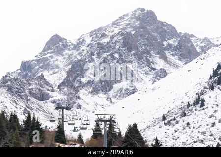 Seggiovia vuota in bassa stagione per lo sci nella stazione sciistica di Shymbulak, vicino Almaty in Kazakistan. Alta vetta coperta di neve. Nessun turista Foto Stock