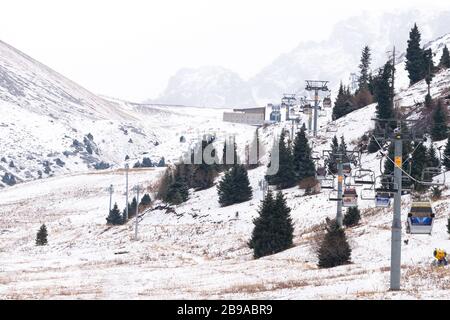 Stazione sciistica di Shymbulak vicino Almaty in inverno con neve. Località montana chiamata anche Chimbulak. Funivia vuota a causa del turismo bassa stagione. Foto Stock