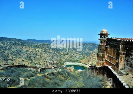 Vista panoramica di uno stagno circondato da splendide colline e cielo blu sullo sfondo, come visto da Jaigarh Fort, Jaipur, India Foto Stock