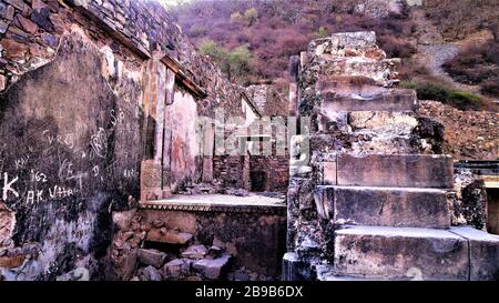 Resti architettonici di fortificazione di Bhangarh rovinata con le colline pinkish belle sullo sfondo, Alwar, Rajasthan, India Foto Stock