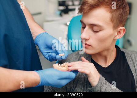 Odontoiatria. Il dentista mostra impianti al paziente. Clinica dentale. Foto Stock