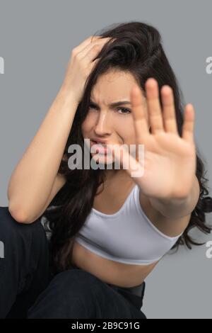 Bella ragazza dai capelli scuri in una parte superiore bianca che guarda stressato Foto Stock