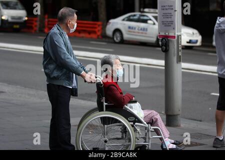 SYDNEY, AUSTRALIA, 24 marzo 2020, un uomo anziano e una donna su una sedia a rotelle sono visti nelle strade del CBD di Sydney a seguito della risposta del governo all’epidemia di coronavirus per chiudere le imprese non essenziali e limitare il contatto fisico tra le persone. Credit: Sebastian Reategui/Alamy Live News Foto Stock