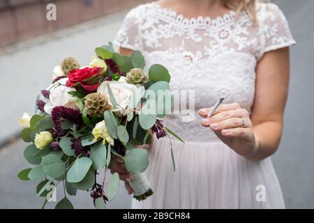 Sposa che tiene bouquet di nozze e sigaretta, fumare il giorno di nozze - concetto di dipendenza Foto Stock