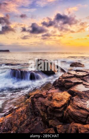 Le rocce di arenaria gialle sulle spiagge del Nord di Sydney intorno a Turimetta si dirigono all'alba. Foto Stock