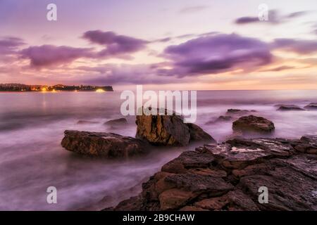 Rocce di arenaria bagnate di Turimetta dirigiti verso le spiagge settentrionali di Sydney all'alba. Foto Stock