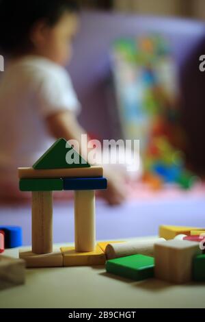 blocco del giocattolo sfocato per il bambino sullo sfondo. attenzione selettiva al castello fatto di blocchi di legno colorati. apprendimento del bambino durante il gioco. cervello e muscolo Foto Stock