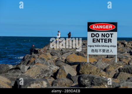 Pescatori regole di rottura pericolo non entrare Entra Breakwall Breakwater Rocks Avviso multilingue Foto Stock