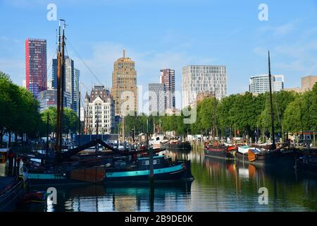 Vecchie barche a vela a fondo piatto nel vecchio porto interno di Rotterdam con numerosi edifici alti sullo sfondo Foto Stock