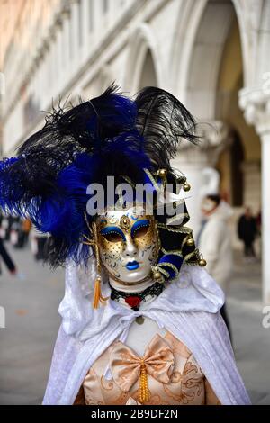 Primo piano di donne mascherate in abiti colorati sullo sfondo del palazzo durante il carnevale veneziano Foto Stock