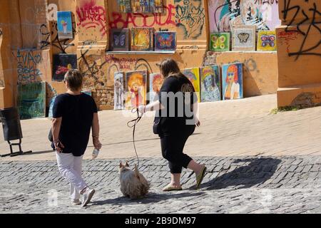 Kiev, Ucraina - 19 maggio 2019: I pedoni camminano oltre un cane per la vendita le opere d'arte sulla strada discesa di Sant'Andrea Foto Stock