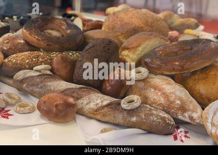 Lotto di focacce e loafs appena sfornati in un banco di mercato. Fabbricazione del pane Foto Stock