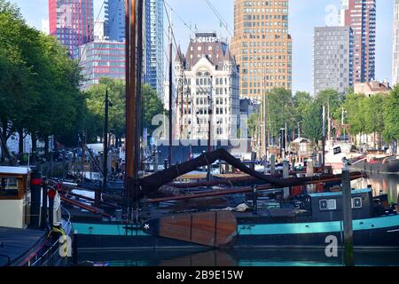 Vecchie barche a vela a fondo piatto nel vecchio porto interno di Rotterdam con numerosi edifici alti sullo sfondo Foto Stock