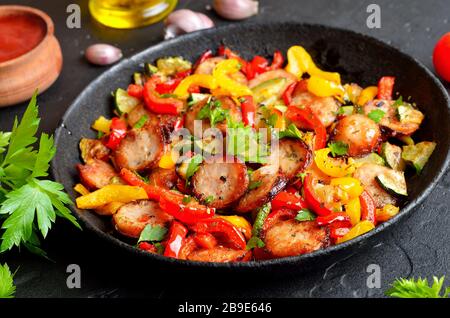 Fette di salsicce fritte con verdure e spezie in padella, vista ravvicinata Foto Stock