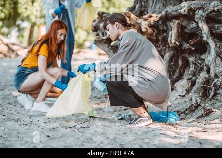 Amici che raccolgono rifiuti dal parco. Essi raccolgono la lettiera in sacco di spazzatura Foto Stock