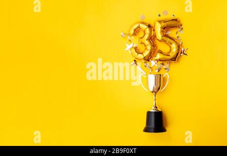 Palloncino numero 35 per la celebrazione dell'anniversario d'oro che esplode da un trofeo vincente Foto Stock