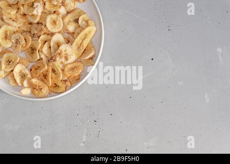 Banana - questo è un colpo di primo piano di una ciotola piena di chip di banana asciugati. Inquadratura con una profondità di campo e vignettatura poco profonda Foto Stock