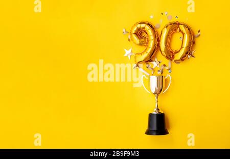 Palloncino numero 90 per la celebrazione dell'anniversario d'oro che esplode da un trofeo vincente Foto Stock