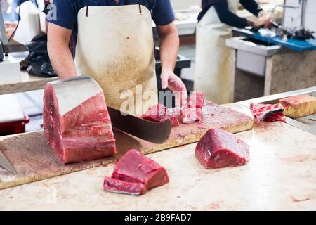 FUNCHAL, PORTOGALLO - 15 FEBBRAIO 2020: Uomo non identificato che taglia il tonno Mercado dos Lavradores (mercato agricolo) a Funchal all'Isola di Madeira, Portogallo. M Foto Stock