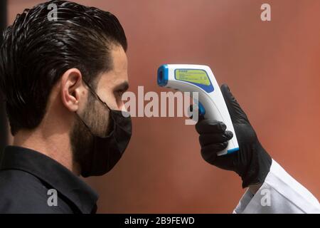 Beirut, Libano. 24 marzo 2020. Gli acquirenti stanno avendo la loro temperatura presa da una pistola termometro per i segni di febbre e sintomi COVID-19 prima di entrare in un supermercato a Beirut. Credit: amer Ghazzal/Alamy Live News Foto Stock
