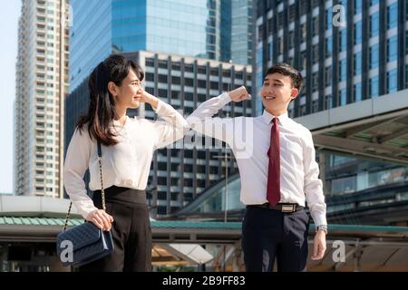 Gomito bump è nuovo saluto per evitare la diffusione di coronavirus. Due amici d'affari asiatici si incontrano di fronte all'edificio degli uffici. Invece di salutare Foto Stock