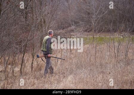 Cacciatore che spara anatre selvatiche su un lago Foto Stock