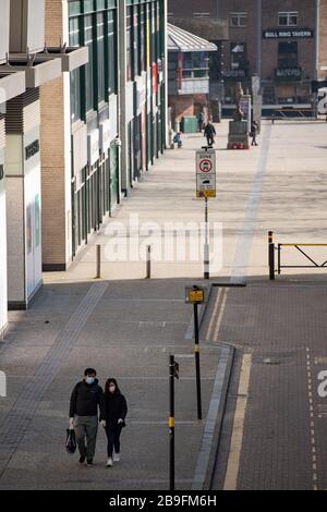 Un paio di persone che indossano attrezzature protettive camminano accanto al Bullring di Birmingham, il giorno dopo che il primo Ministro Boris Johnson ha messo il Regno Unito in una situazione di blocco per contribuire a frenare la diffusione del coronavirus. Foto Stock