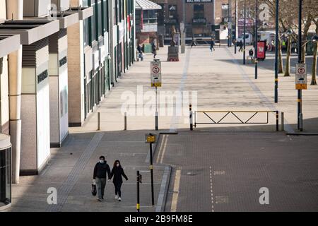 Un paio di persone che indossano attrezzature protettive camminano accanto al Bullring di Birmingham, il giorno dopo che il primo Ministro Boris Johnson ha messo il Regno Unito in una situazione di blocco per contribuire a frenare la diffusione del coronavirus. Foto Stock