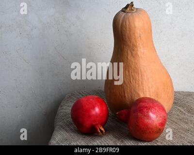 Ancora vita di zucca e melograno su burlap in luce naturale Foto Stock