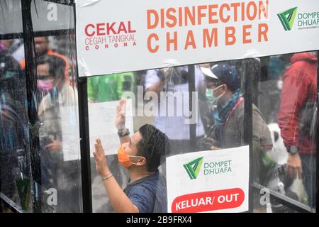 Giacarta, Indonesia. 24 Marzo 2020. La gente prova la camera di disinfezione collocata nelle aree pubbliche per impedire la diffusione del coronavirus a Jakarta, Indonesia, 24 marzo 2020. Il numero totale di decessi dovuti alla pandemia COVID-19 in Indonesia è stato superiore a 50 entro le 12:00 (ora locale) di martedì, secondo il governo indonesiano. Credit: Zulkarnain/Xinhua/Alamy Live News Foto Stock