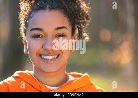 Ritratto all'aperto di bella Happy gara mista African American ragazza adolescente femmina giovane donna sorridente con denti perfetti al sole della sera d'oro Foto Stock