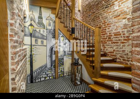 Scala in legno e tappeto grigio. Interno loft moderno di un ingresso di un edificio di appartamenti. Muro di mattoni. Foto Stock