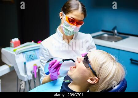 Bella donna paziente avente il trattamento dentale al dentista dell'ufficio. Donna visitando il suo dentista Foto Stock