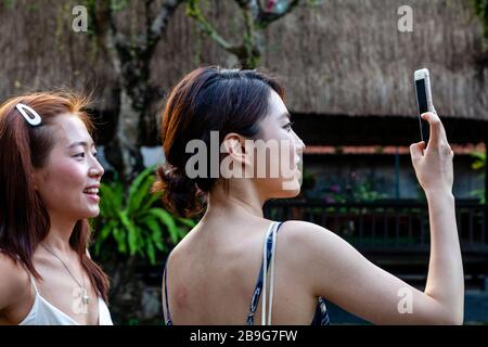 Turisti asiatici che prendono le foto a pura Taman Saraswati, Bali, Indonesia. Foto Stock