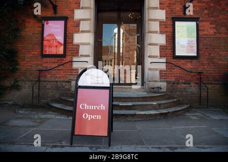 Un segno fuori dalla chiesa della Santissima Trinità a Guildford che dichiara che è aperta tuttavia ha chiuso il giorno dopo che il primo ministro Boris Johnson ha messo il Regno Unito in blocco per contribuire a frenare la diffusione del coronavirus. Foto Stock