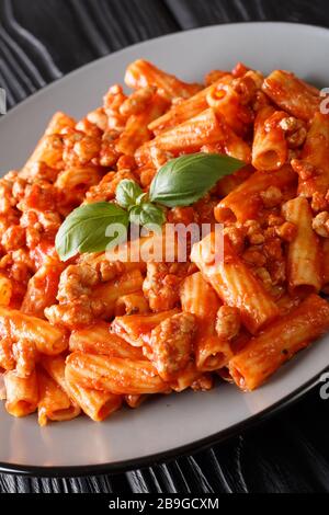 Gustosa Tortiglioni bolognese con basilico primo piano in un piatto sul tavolo. Verticale Foto Stock