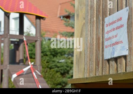 19 marzo 2020, Sassonia, Belgershain: 'rispetto alla situazione attuale, il parco giochi rimarrà chiuso ad eccezione di Weioteres' è scritto su diversi cartelli su un parco giochi per bambini nel quartiere di Lipsia, che è chiuso con una banda rossa e bianca. Foto: Volkmar Heinz/dpa-Zentralbild/ZB Foto Stock