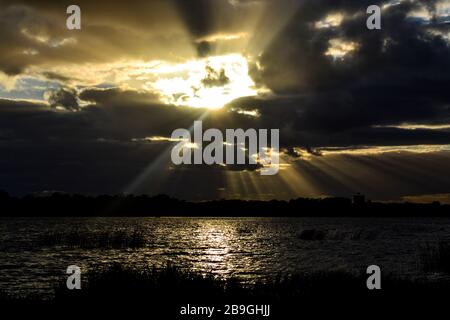 Bellissimo paesaggio al tramonto con raggi di sole che brillano attraverso le nuvole Foto Stock