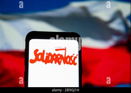 Polonia. 23 marzo 2020. In questa illustrazione della foto viene visualizzato un logo Solidarnosc (Solidarity) sullo smartphone.la bandiera nazionale polacca viene visualizzata come sfondo. Credit: Mateusz Slodkowski/SOPA Images/ZUMA Wire/Alamy Live News Foto Stock