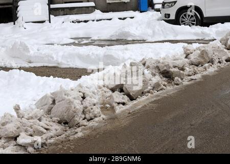 Strade non pulite con forti innevamento dopo la caduta di neve in città, auto sotto la neve. Foto Stock