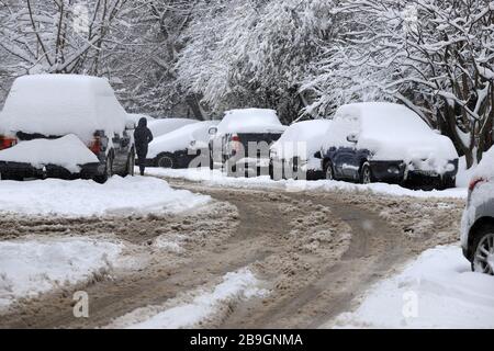 Strade non pulite con forti innevamento dopo la caduta di neve in città, auto sotto la neve. Foto Stock