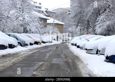 Strade non pulite con forti innevamento dopo la caduta di neve in città, auto sotto la neve. Foto Stock