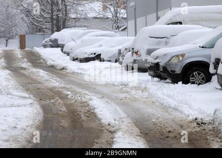 Strade non pulite con forti innevamento dopo la caduta di neve in città, auto sotto la neve. Foto Stock