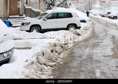 Strade non pulite con forti innevamento dopo la caduta di neve in città, auto sotto la neve. Foto Stock